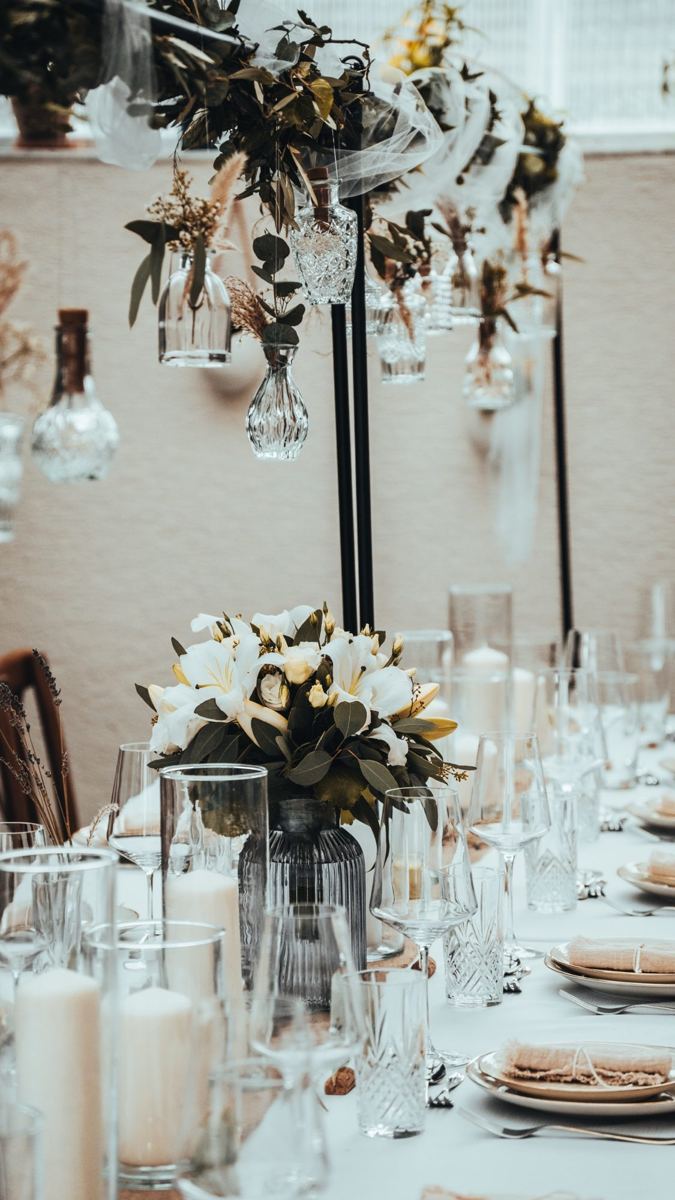 Hochzeitstafel mit hängenden Glasflaschen und Blumendeko