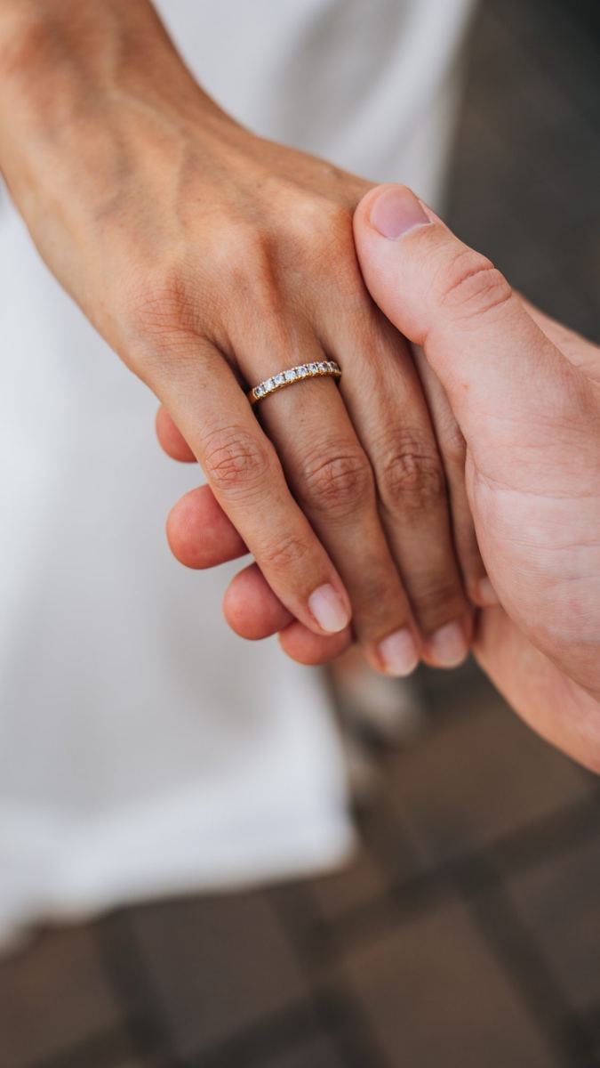 Bräutigam hält die Hand der Braut, der Ehering im Fokus