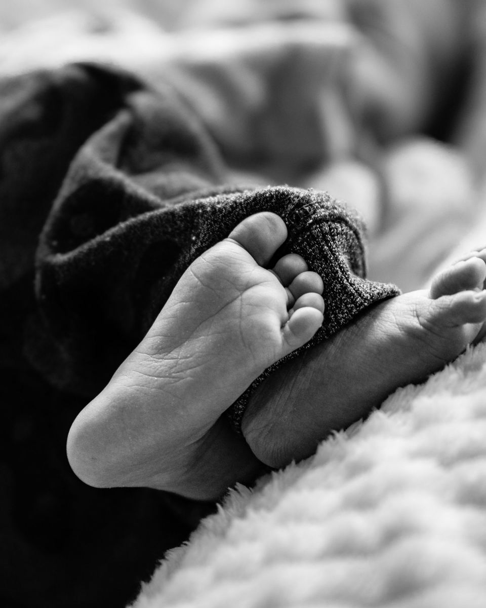 Schwarz-Weiß-Aufnahme: Babyfüßchen im Strampler
